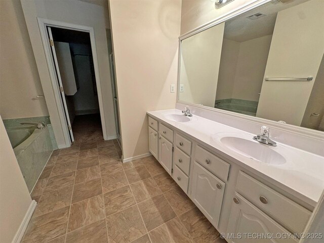 7333 W 36th St, Tulsa, OK 74107 - bathroom featuring double vanity, a garden tub, baseboards, and stone finish flooring