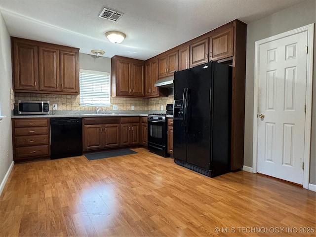 2836 E Admiral Blvd, Tulsa, OK 74110 - kitchen with black appliances, light wood finished floors, and backsplash