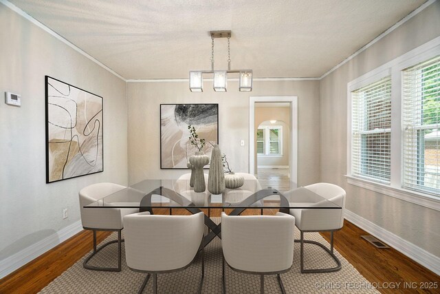 1648 S Columbia Pl, Tulsa, OK 74104 - dining room featuring crown molding, plenty of natural light, baseboards, wood finished floors, and a textured ceiling