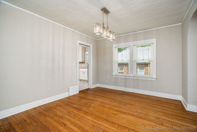 1648 S Columbia Pl, Tulsa, OK 74104 - spare room featuring ornamental molding, a chandelier, a textured ceiling, baseboards, and wood finished floors
