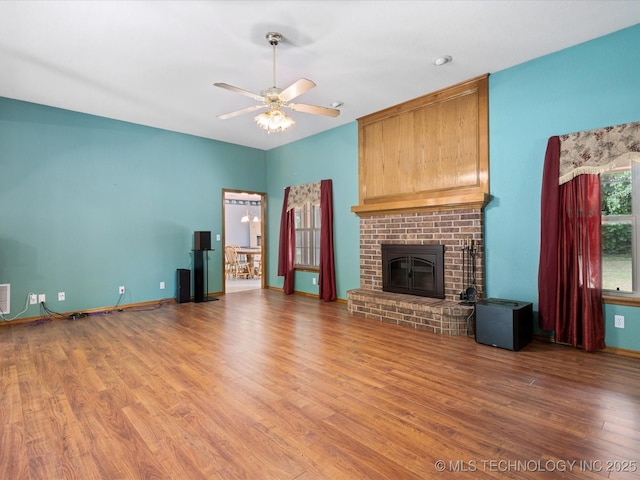 1310 Prairie Heights Dr, Bartlesville, OK 74006 - unfurnished living room with wood finished floors, a ceiling fan, a brick fireplace, and baseboards