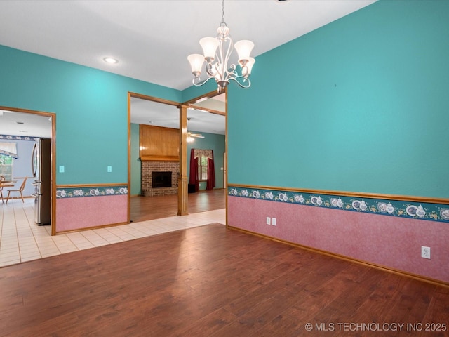 1310 Prairie Heights Dr, Bartlesville, OK 74006 - unfurnished living room with wood finished floors, a chandelier, a fireplace, and baseboards