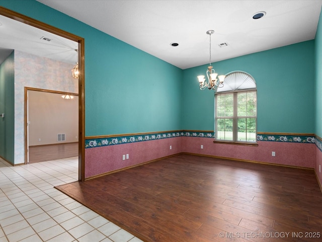 1310 Prairie Heights Dr, Bartlesville, OK 74006 - empty room featuring a chandelier, hardwood / wood-style flooring, wallpapered walls, a wainscoted wall, and baseboards