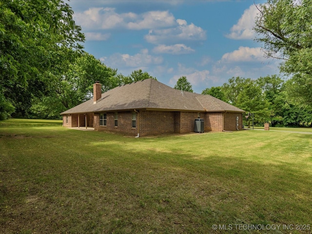 1310 Prairie Heights Dr, Bartlesville, OK 74006 - view of side of home featuring a yard, a chimney, brick siding, and view of wooded area