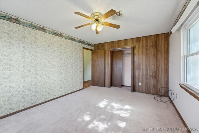 20600 Slick Rd, Kellyville, OK 74039 - unfurnished bedroom featuring carpet, wooden walls, ceiling fan, and a closet
