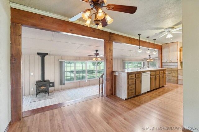 20600 Slick Rd, Kellyville, OK 74039 - kitchen featuring white dishwasher, light wood-style flooring, a wood stove, a ceiling fan, and hanging light fixtures