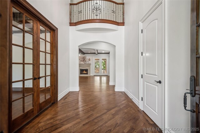 11408 S Harvard Ave, Tulsa, OK 74137 - foyer entrance with french doors, arched walkways, dark wood-style flooring, baseboards, and a lit fireplace