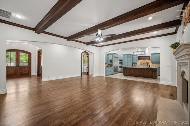 11408 S Harvard Ave, Tulsa, OK 74137 - unfurnished living room with arched walkways, wood finished floors, a ceiling fan, beam ceiling, and baseboards
