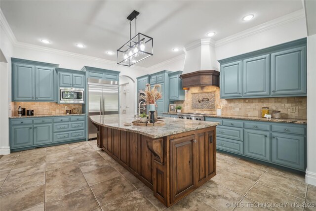 11408 S Harvard Ave, Tulsa, OK 74137 - kitchen featuring built in appliances, blue cabinets, tasteful backsplash, custom exhaust hood, and decorative light fixtures