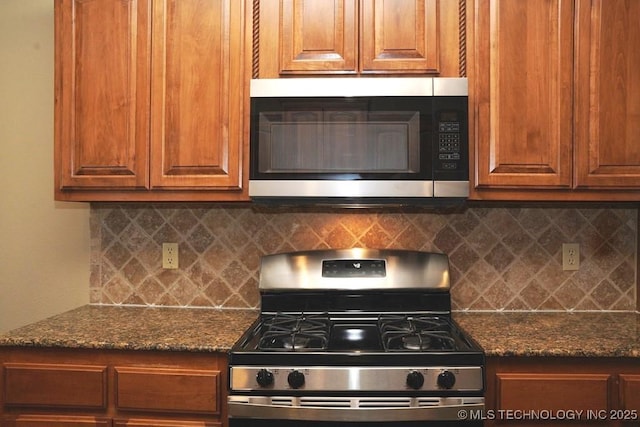 717 W 39th St, Sand Springs, OK 74063 - kitchen featuring appliances with stainless steel finishes, tasteful backsplash, brown cabinetry, and dark stone counters