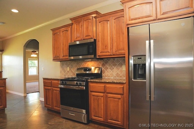 717 W 39th St, Sand Springs, OK 74063 - kitchen featuring appliances with stainless steel finishes, ornamental molding, tasteful backsplash, dark stone counters, and dark tile patterned flooring
