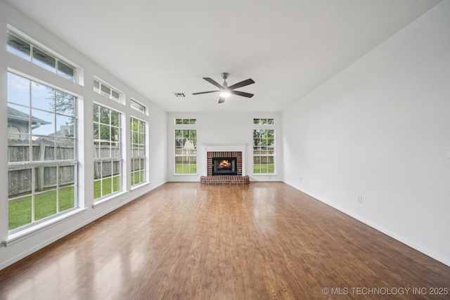 unfurnished living room with plenty of natural light, wood finished floors, ceiling fan, and baseboards