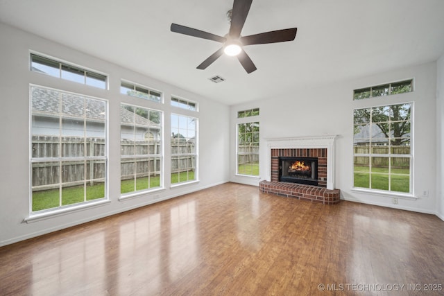 unfurnished living room featuring wood finished floors, baseboards, a fireplace, and a ceiling fan