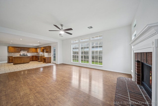 unfurnished living room with a fireplace, a ceiling fan, light wood finished floors, baseboards, and recessed lighting