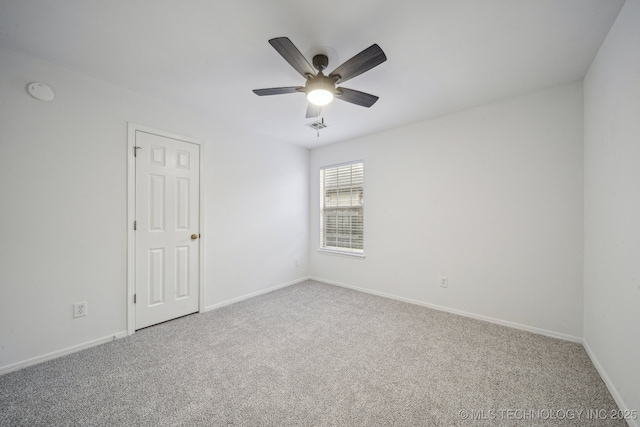 spare room with carpet floors, a ceiling fan, and baseboards