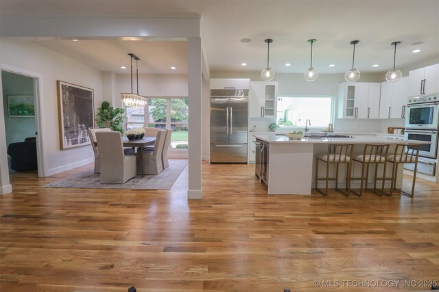 2503 S Birmingham Ave, Tulsa, OK 74114 - kitchen featuring appliances with stainless steel finishes, a warming drawer, light wood-type flooring, plenty of natural light, and recessed lighting