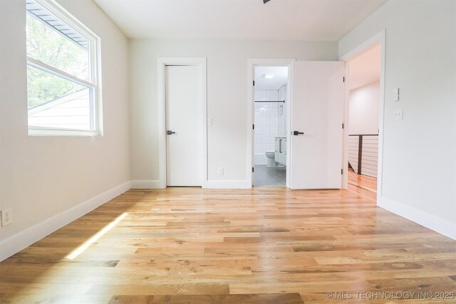 2503 S Birmingham Ave, Tulsa, OK 74114 - unfurnished bedroom featuring light wood finished floors, ensuite bathroom, and baseboards