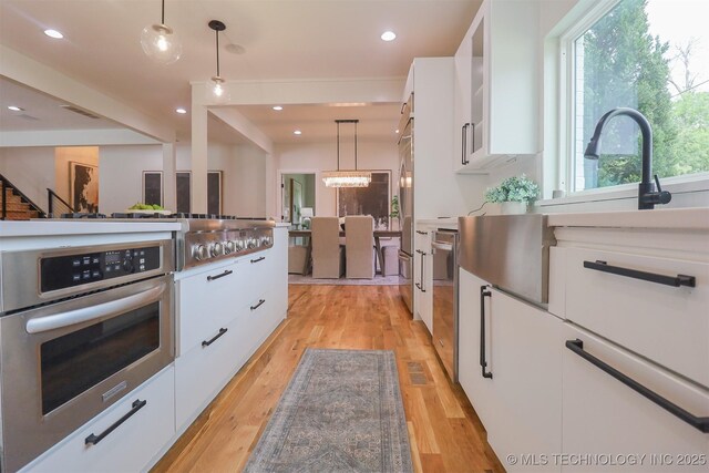 2503 S Birmingham Ave, Tulsa, OK 74114 - kitchen featuring white cabinets, stainless steel appliances, decorative light fixtures, light wood-type flooring, and recessed lighting