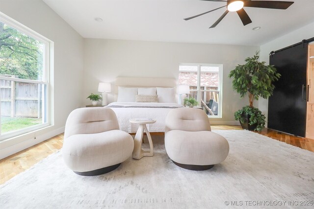 2503 S Birmingham Ave, Tulsa, OK 74114 - bedroom with a barn door, multiple windows, and wood finished floors