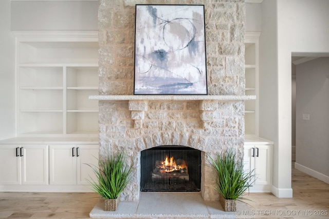 detailed view of a stone fireplace, wood finished floors, and baseboards