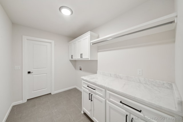washroom with cabinet space, washer hookup, baseboards, and light tile patterned flooring