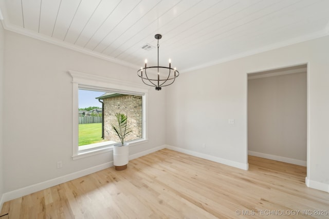 spare room with a chandelier, ornamental molding, light wood finished floors, and baseboards
