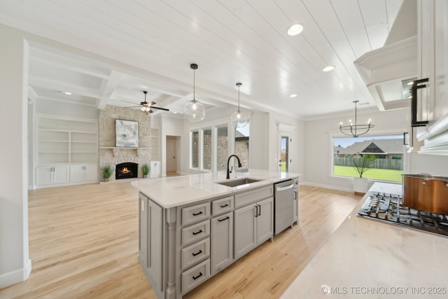 kitchen with a sink, a large fireplace, appliances with stainless steel finishes, ceiling fan, and gray cabinets