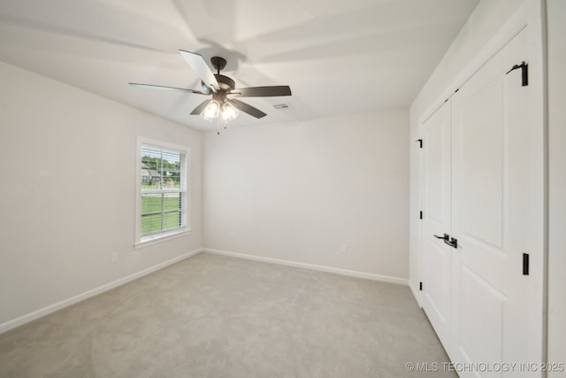 unfurnished bedroom with baseboards, light colored carpet, a closet, and a ceiling fan