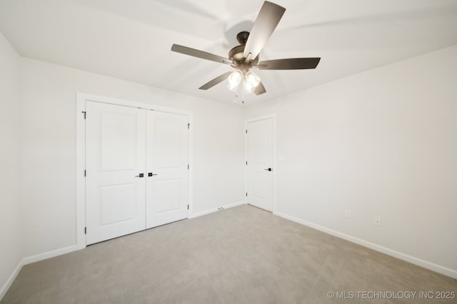unfurnished bedroom featuring light colored carpet, baseboards, a closet, and a ceiling fan