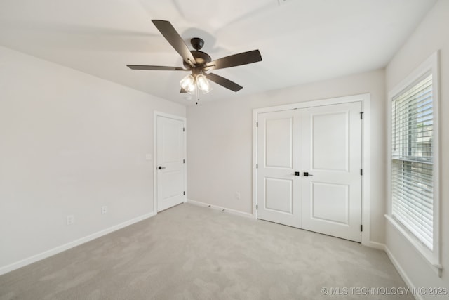 unfurnished bedroom with light colored carpet, baseboards, and ceiling fan