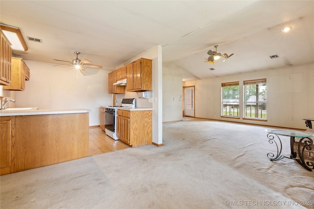 kitchen with gas stove, a ceiling fan, a sink, light carpet, and baseboards