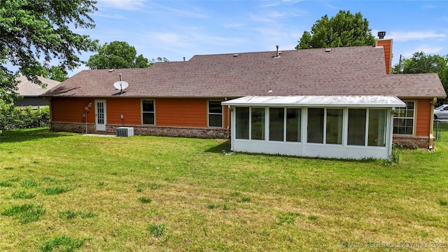back of house featuring a chimney, a sunroom, central AC, and a lawn