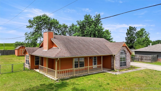 view of front of house with covered porch, a storage shed, a chimney, a gate, and an outdoor structure