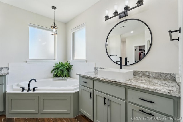 9429 Bryan Rd, Shawnee, OK 74855 - full bathroom featuring vanity, healthy amount of natural light, a garden tub, and wood finished floors