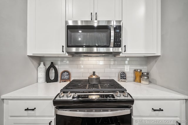kitchen featuring appliances with stainless steel finishes, white cabinetry, decorative backsplash, and light stone counters
