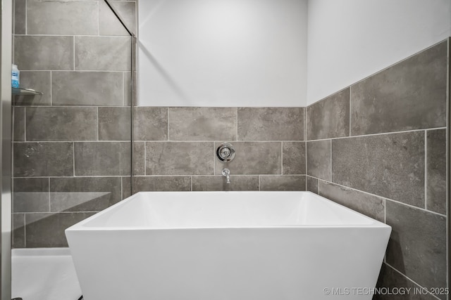 bathroom featuring a soaking tub and tile walls