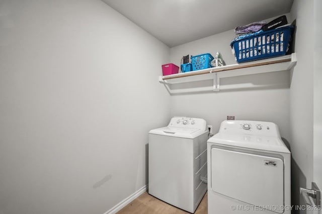 laundry room featuring washer and dryer, light wood-style flooring, and baseboards