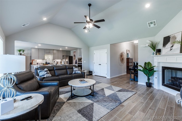15922 E 75th Pl N, Owasso, OK 74055 - living area with dark wood-style flooring, a ceiling fan, high vaulted ceiling, a glass covered fireplace, and recessed lighting