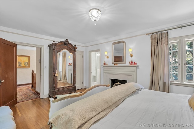 2815 S Woodward Blvd, Tulsa, OK 74114 - bedroom featuring wood finished floors, a brick fireplace, baseboards, and ensuite bath