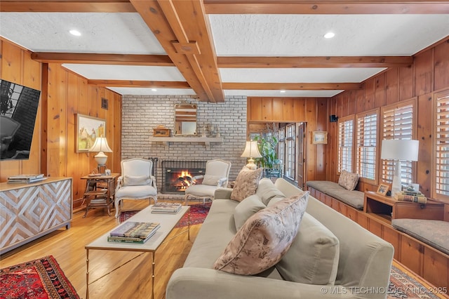 2815 S Woodward Blvd, Tulsa, OK 74114 - living room with beamed ceiling, wood finished floors, wooden walls, a fireplace, and a textured ceiling