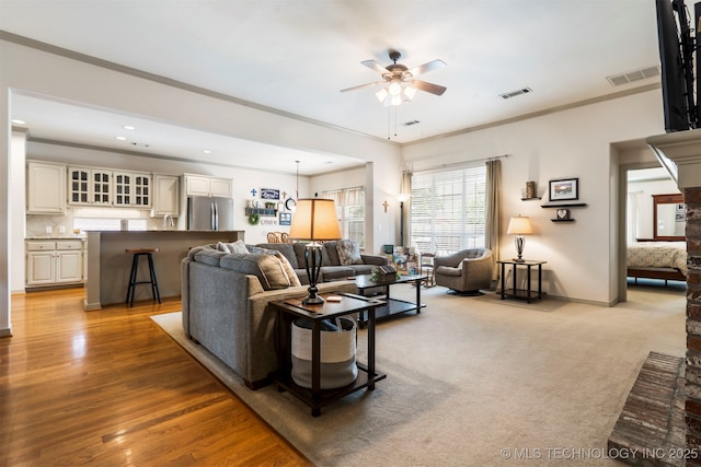 living area featuring ceiling fan, baseboards, ornamental molding, recessed lighting, and wood finished floors