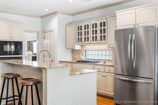 kitchen featuring appliances with stainless steel finishes, a kitchen breakfast bar, light stone countertops, tasteful backsplash, and glass insert cabinets