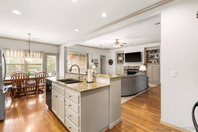 kitchen with a sink, dishwasher, ceiling fan, a fireplace, and light wood-style flooring