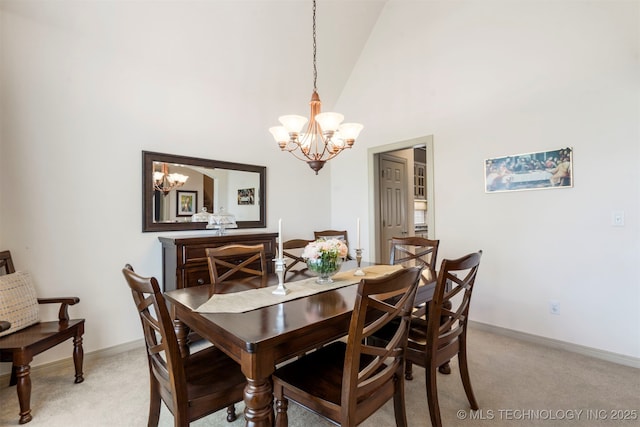dining space featuring a chandelier, light colored carpet, baseboards, and high vaulted ceiling