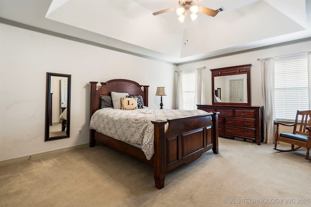 bedroom featuring light carpet, a tray ceiling, ceiling fan, and baseboards