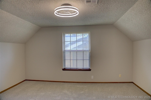 8242 S Sandusky Ave, Tulsa, OK 74137 - additional living space with vaulted ceiling, a textured ceiling, light carpet, and baseboards