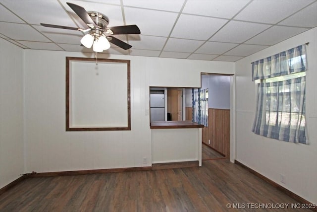 unfurnished room with a drop ceiling, wood finished floors, baseboards, and a ceiling fan