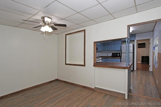empty room featuring wood finished floors, ceiling fan, a paneled ceiling, and baseboards