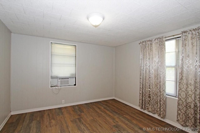 unfurnished room with wood finished floors, cooling unit, and baseboards