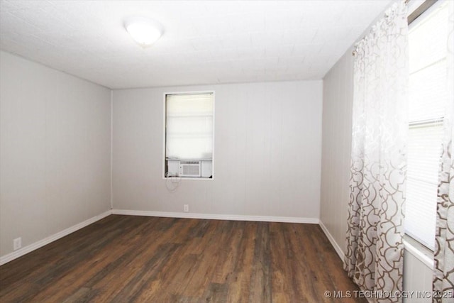 empty room featuring wood finished floors, baseboards, and cooling unit